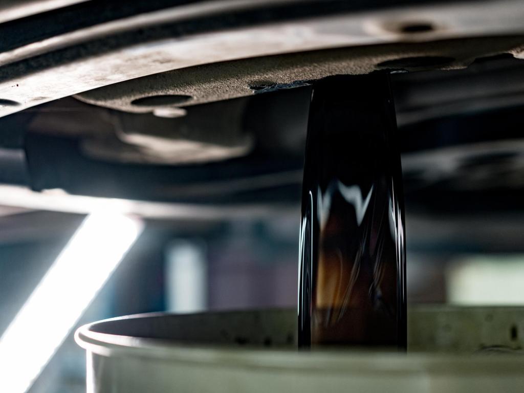 The underside of a vehicle, draining motor oil into an oil pan